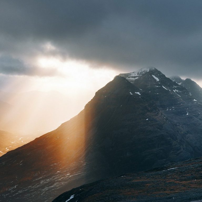 Mountain peak under dramatic clouds, with sunlight breaking through. Psychotherapy North Wales
